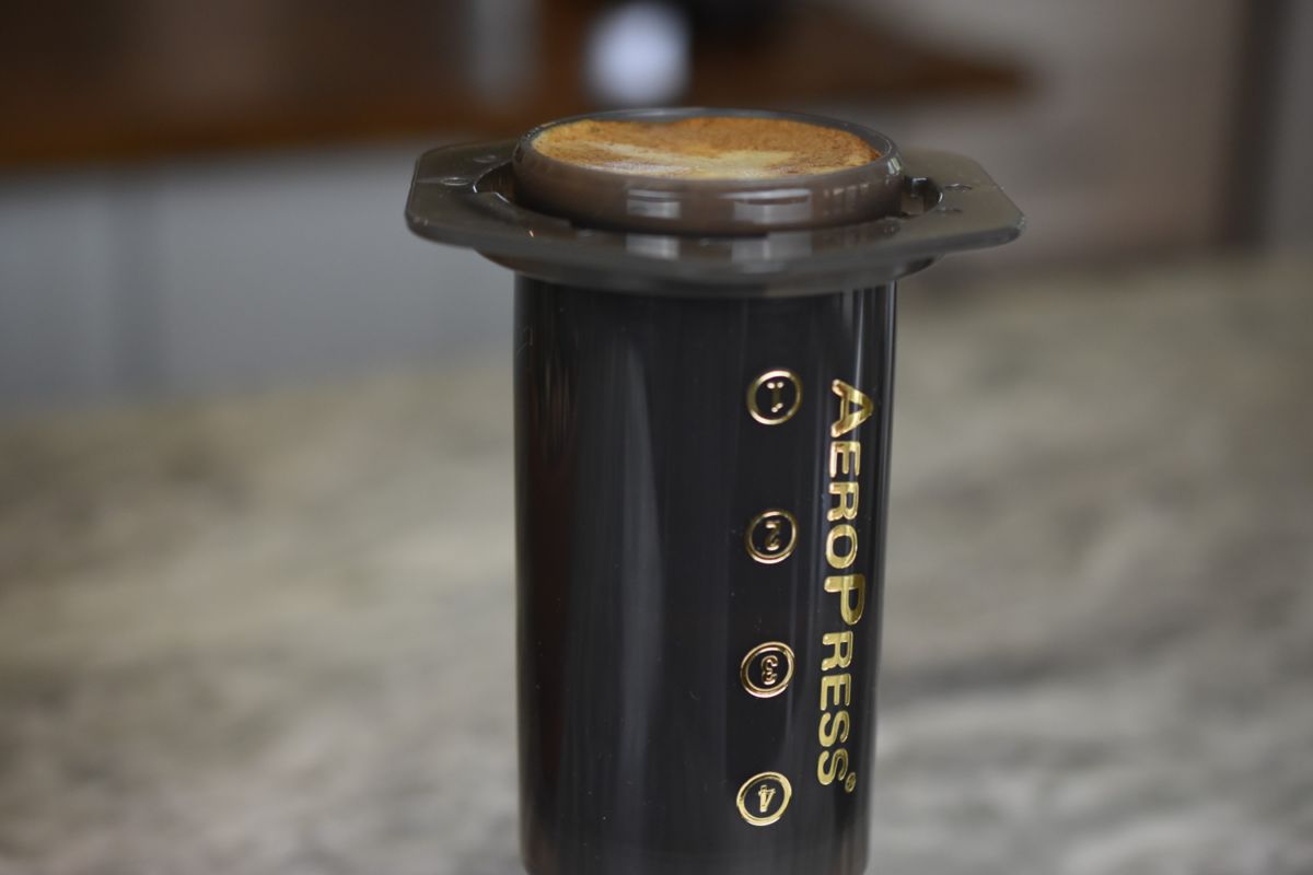 Aeropress coffee maker with a coffee puck on a blurred background