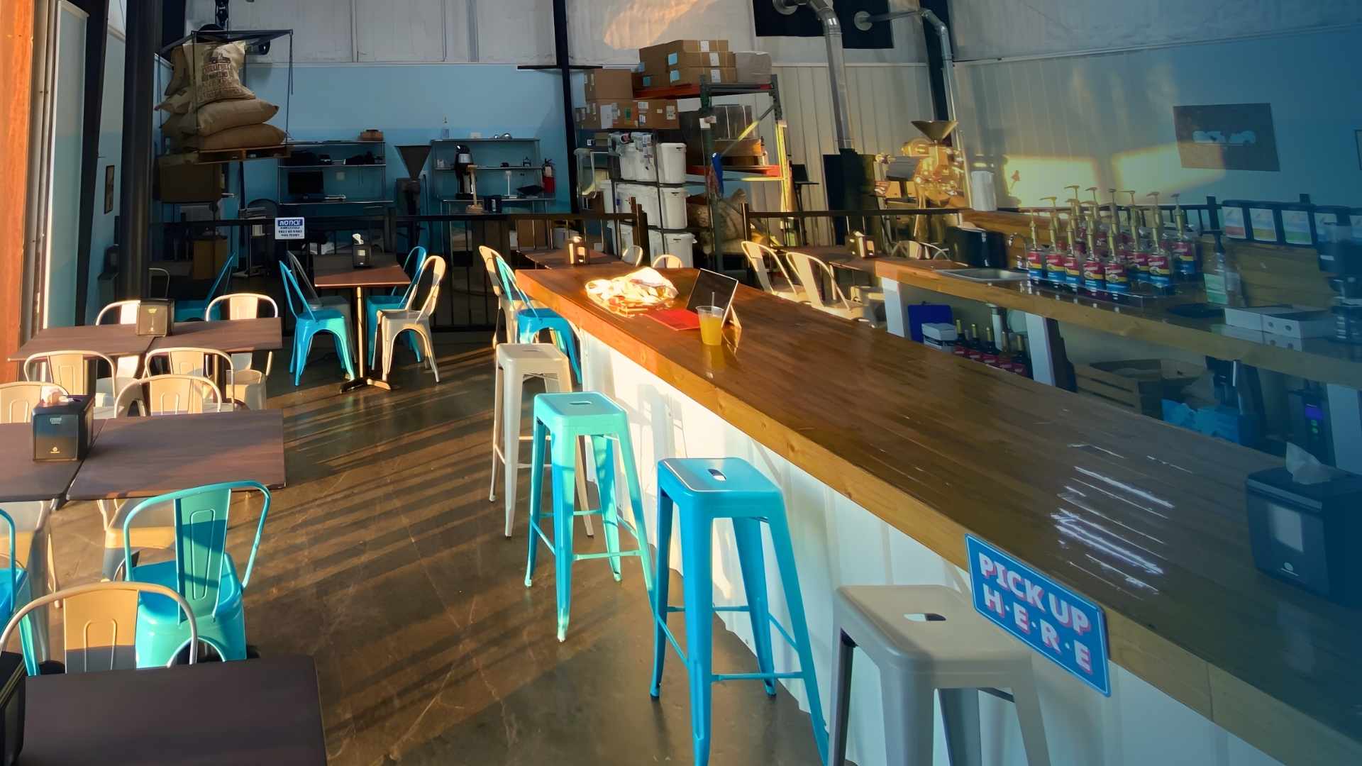 Bar area with blue stools, tables, and a counter in a casual dining setting.